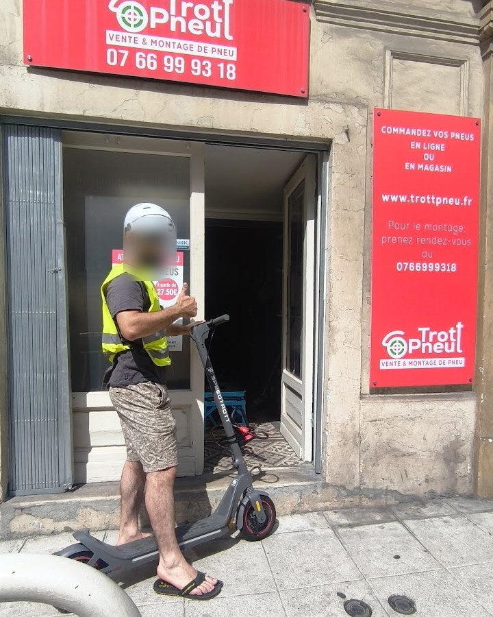 Client casqué devant la vitrine Trott Pneu, montage de pneu à Nice