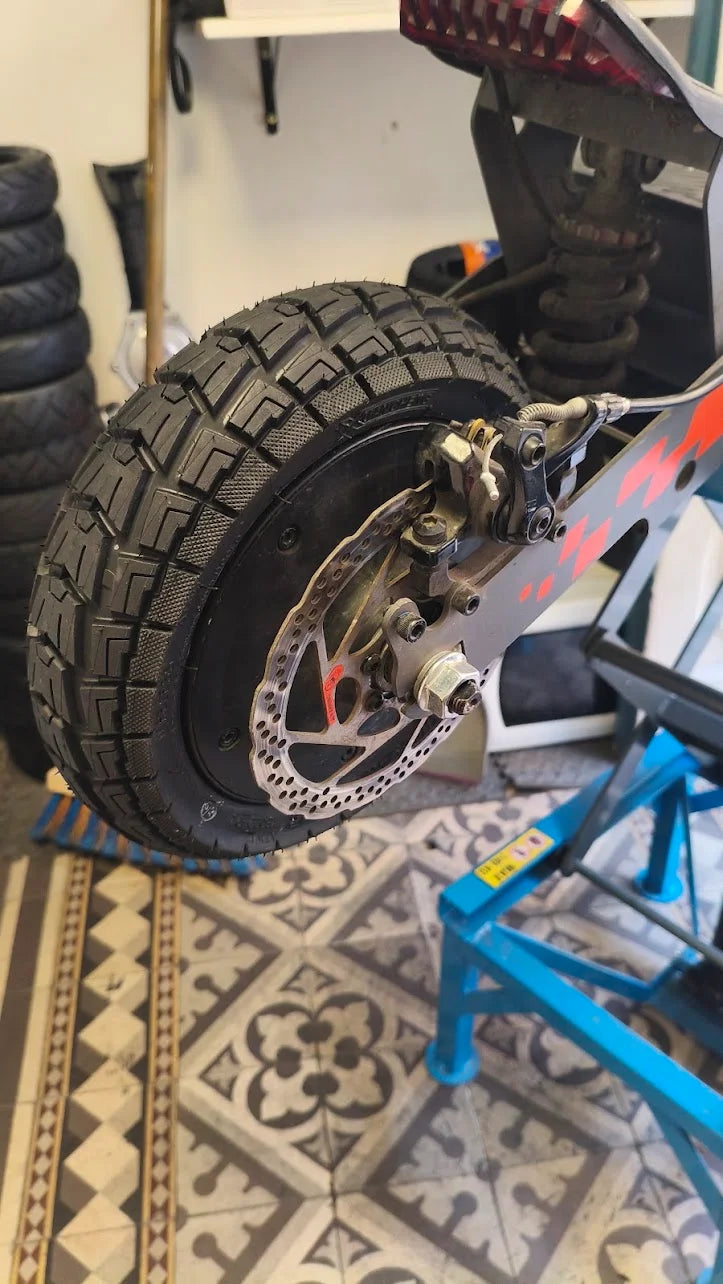 Pneu 10x2,75-6.5 gel posé à l'atelier, trottinette en arrière-plan