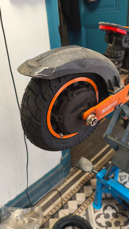 Roue de trottinette équipée du pneu 10x3-6, disque de frein visible, en atelier