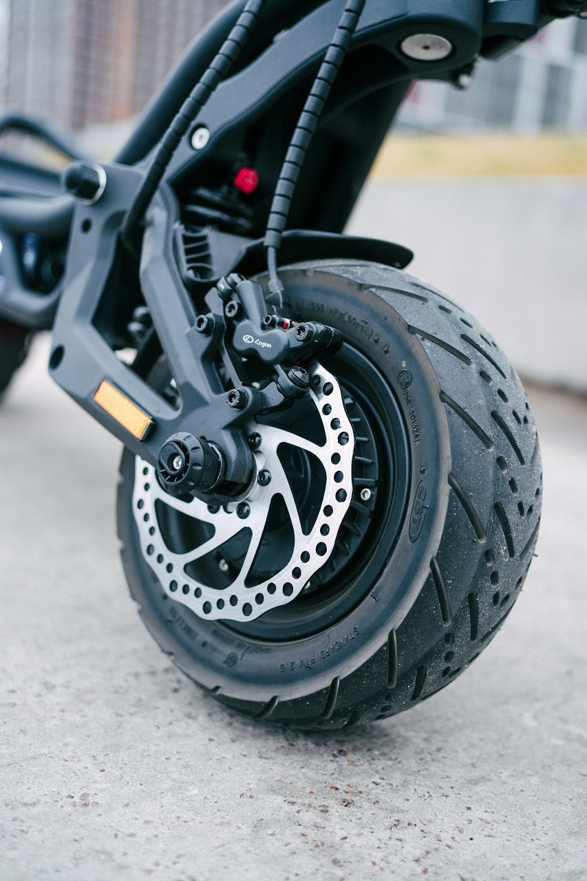 Pneu de trottinette électrique noir avec jante, gros plan sur la bande de roulement.